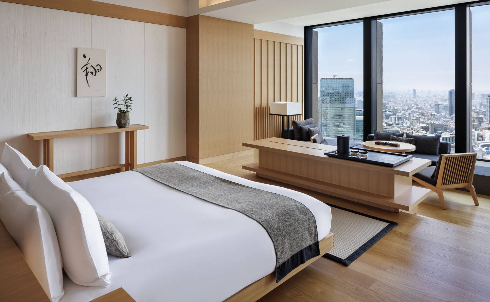 東京安縵｜套房臥室的大床、掛軸與市景落地窗