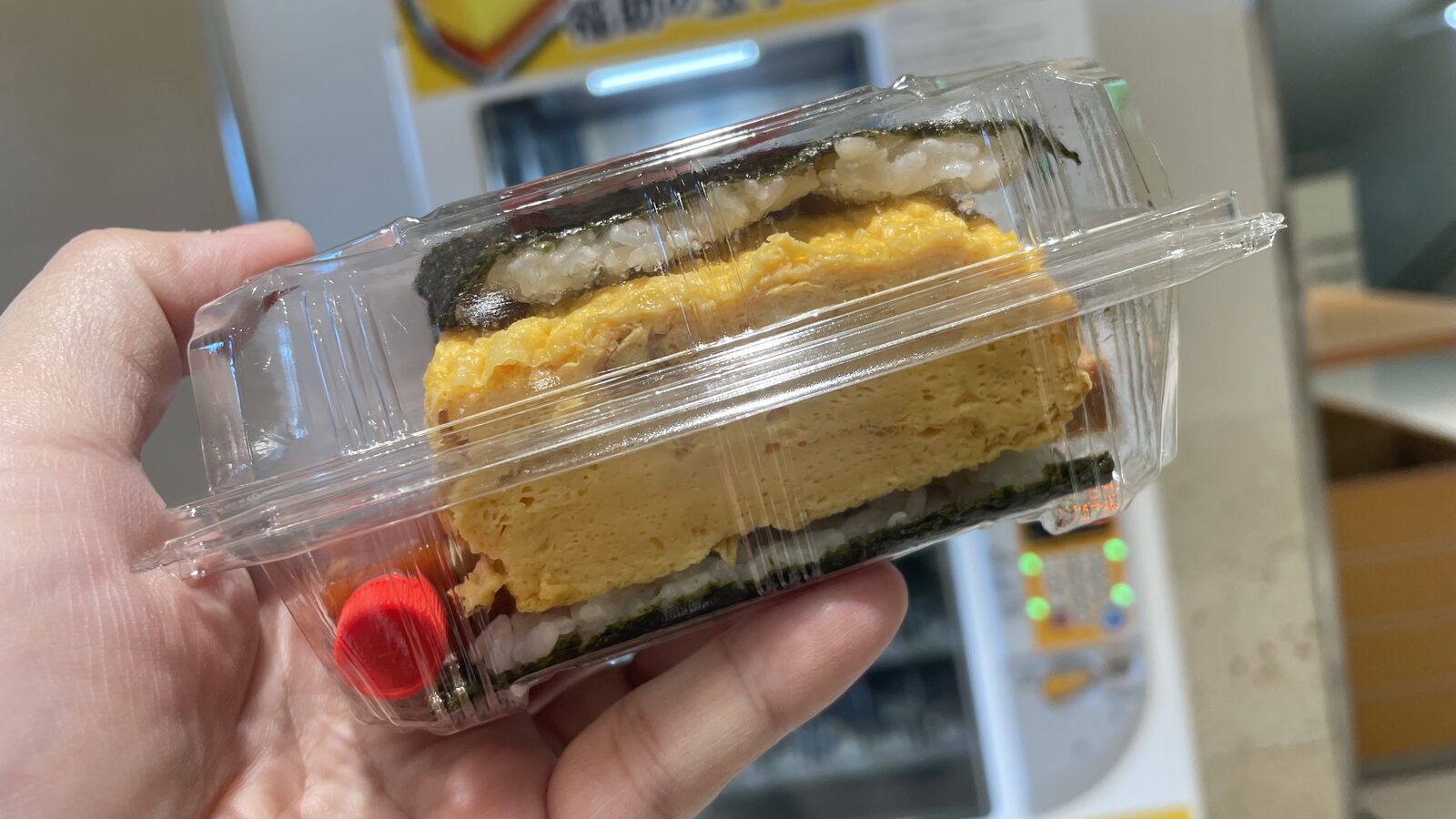 透明餐盒內厚切玉子燒、午餐肉、白飯與海苔組成的飯糰