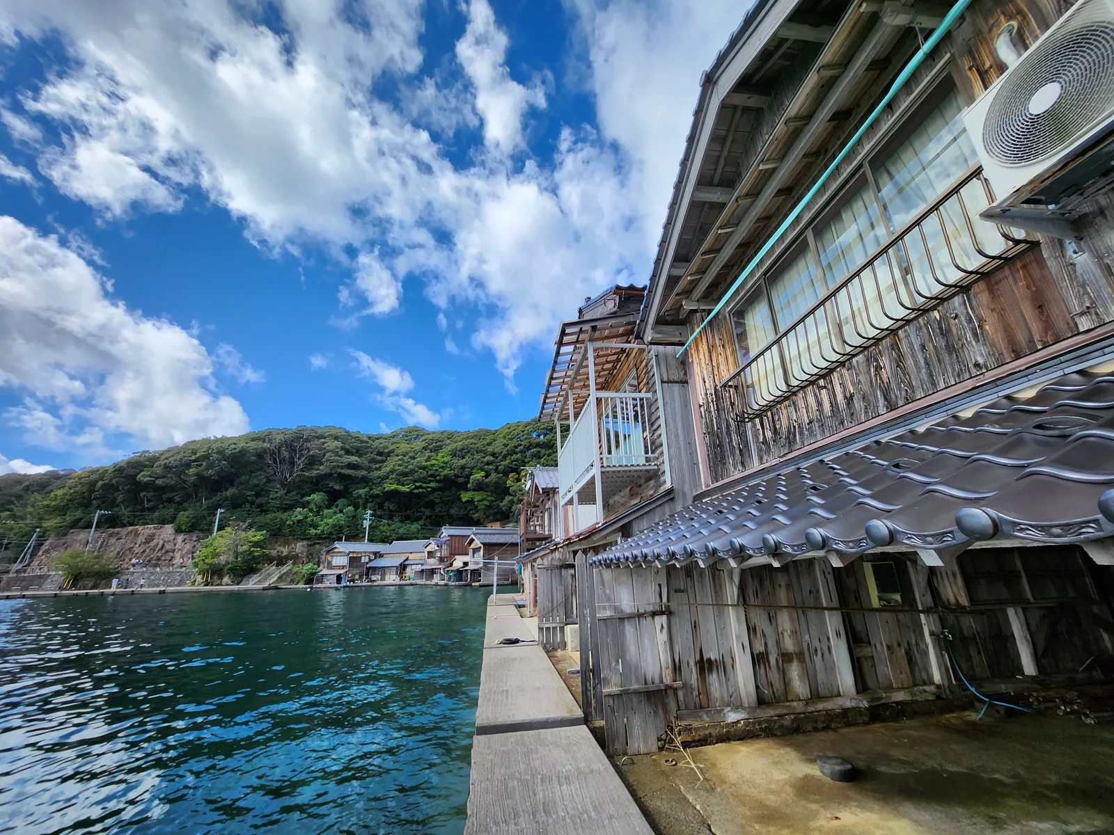 從海邊近距離拍攝伊根木造舟屋與停泊小船