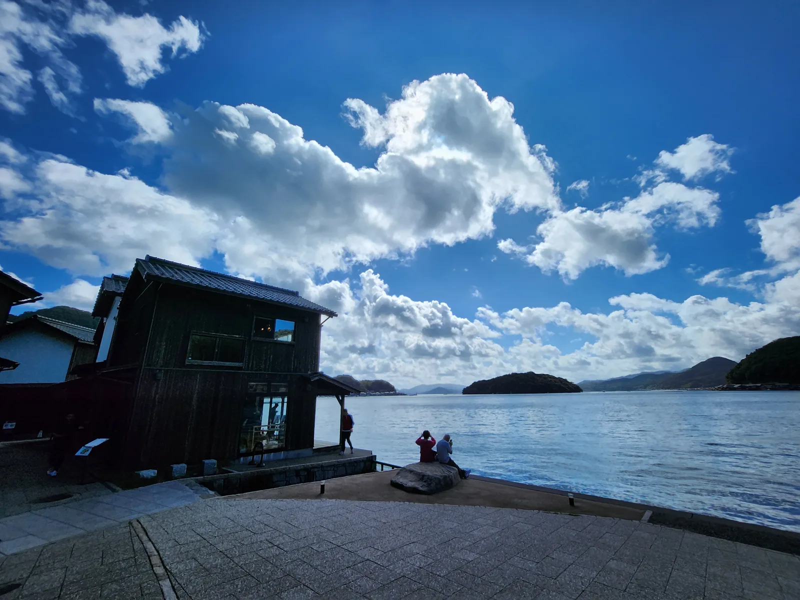 伊根灣水岸獨立木造舟屋與旅客散步景色