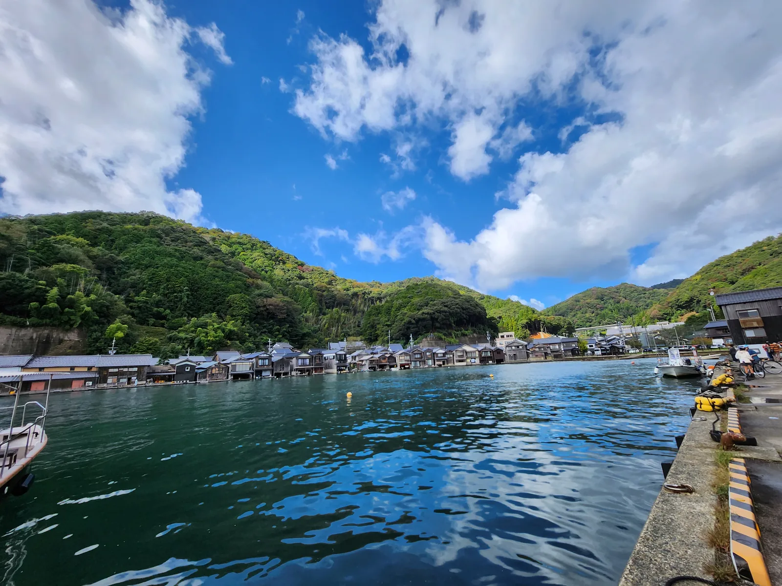 伊根港藍色海面、漁船與沿岸舟屋群全景