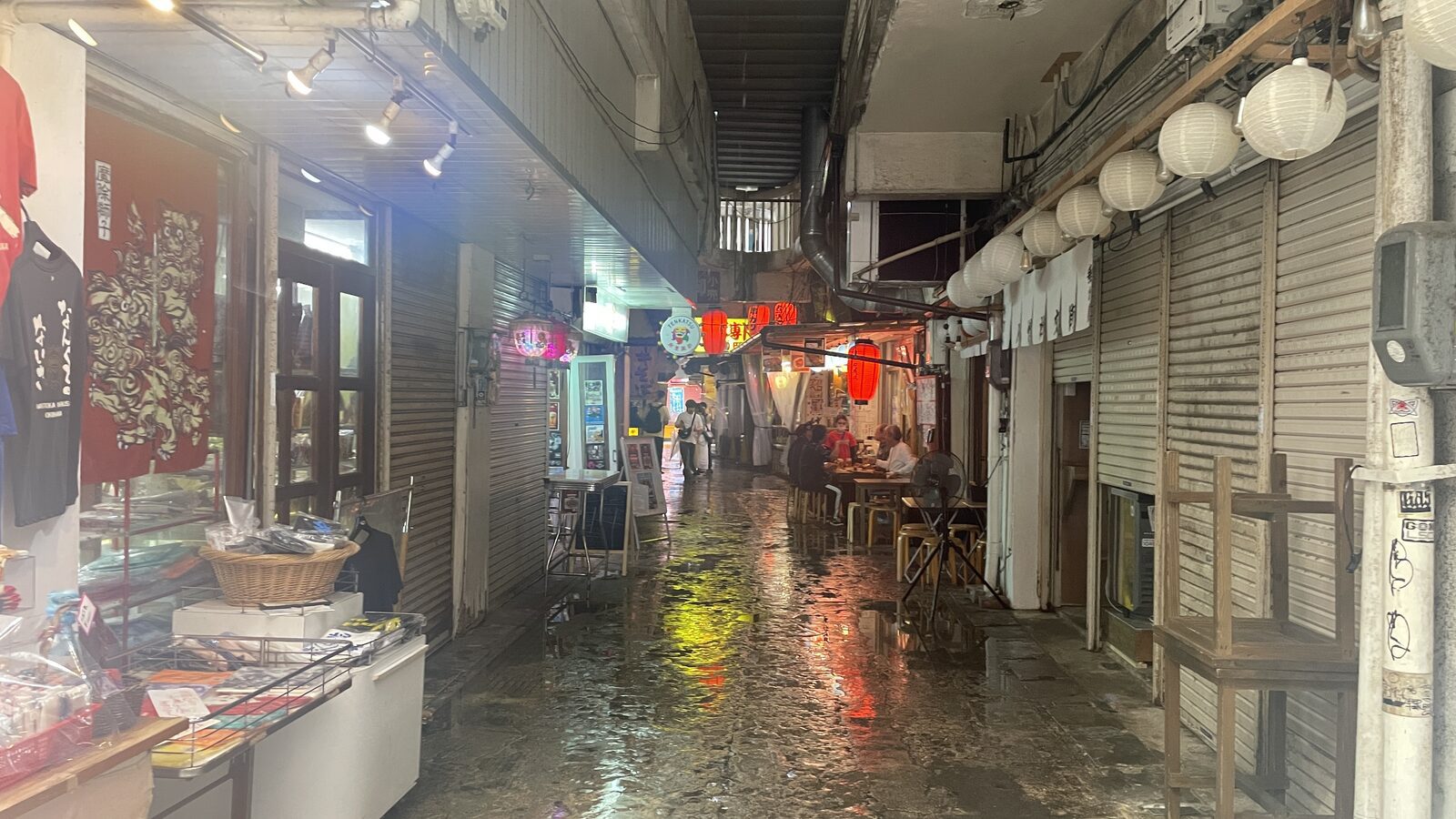 下雨後市場周邊巷弄地面反射燈光，兩側為小店