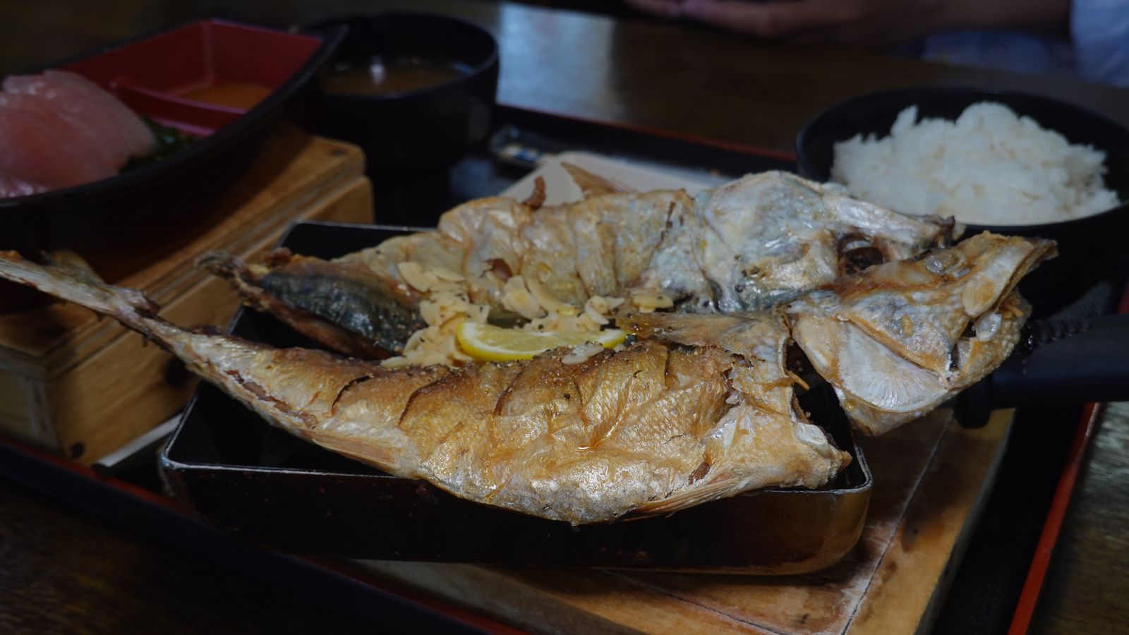 鐵板上滋滋作響的奶油烤魚特寫,搭配大量蒜片與新鮮檸檬