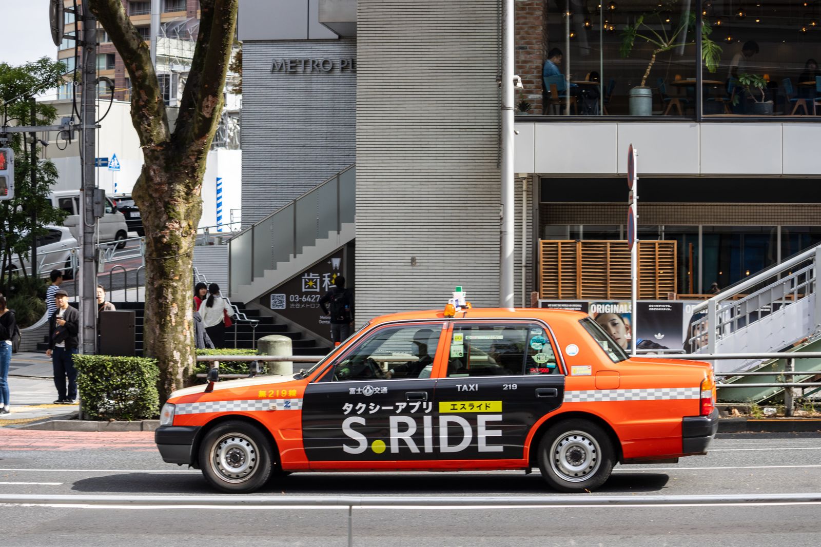 東京街頭貼有 S.RIDE 廣告的橘色日本計程車