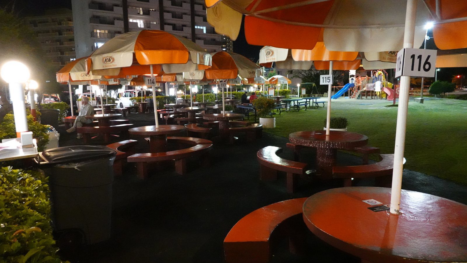 A&W 牧港店夜間戶外圓桌座位與橘白遮棚