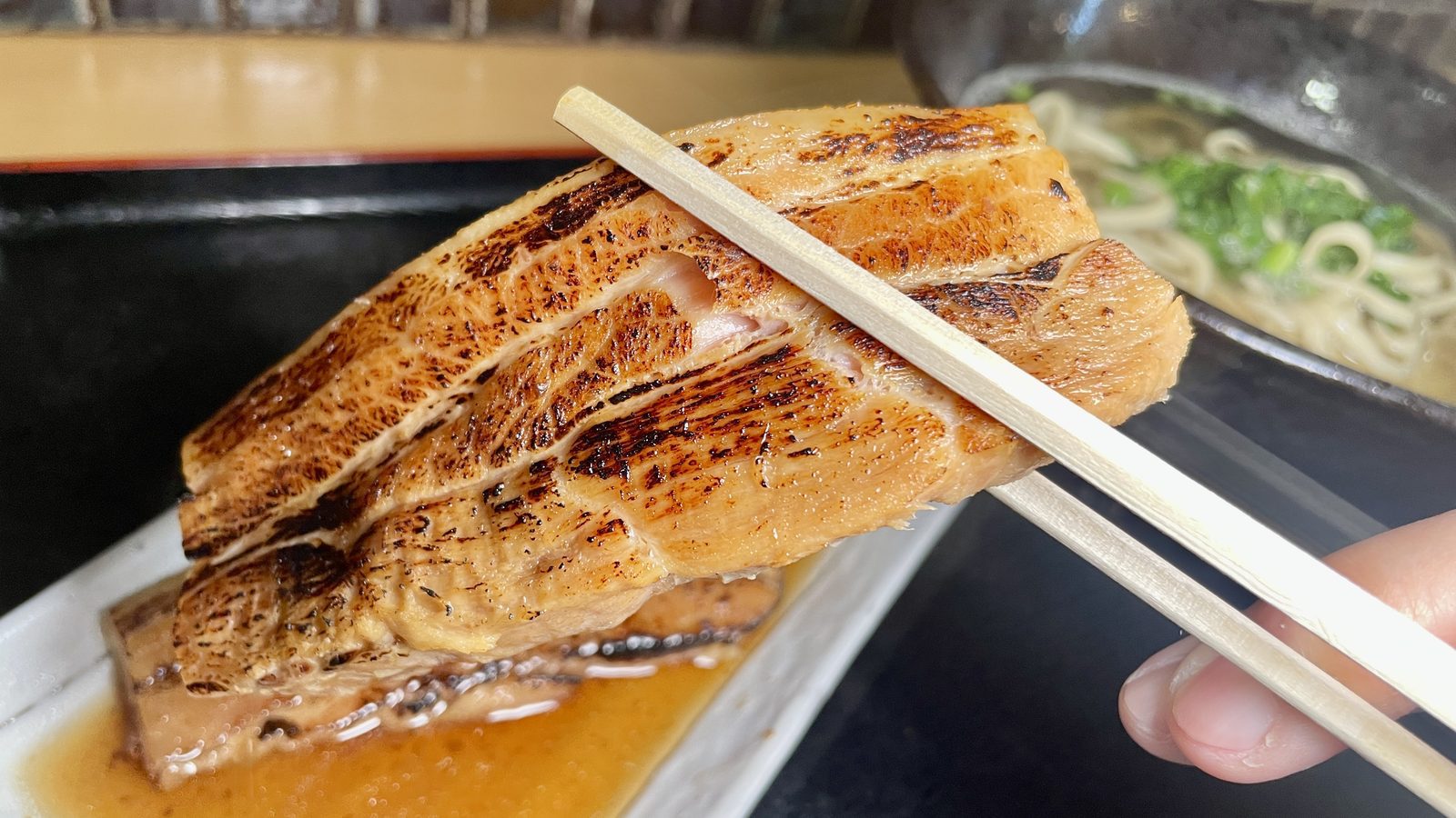 用筷子夾起厚實焦香的炙燒三層肉