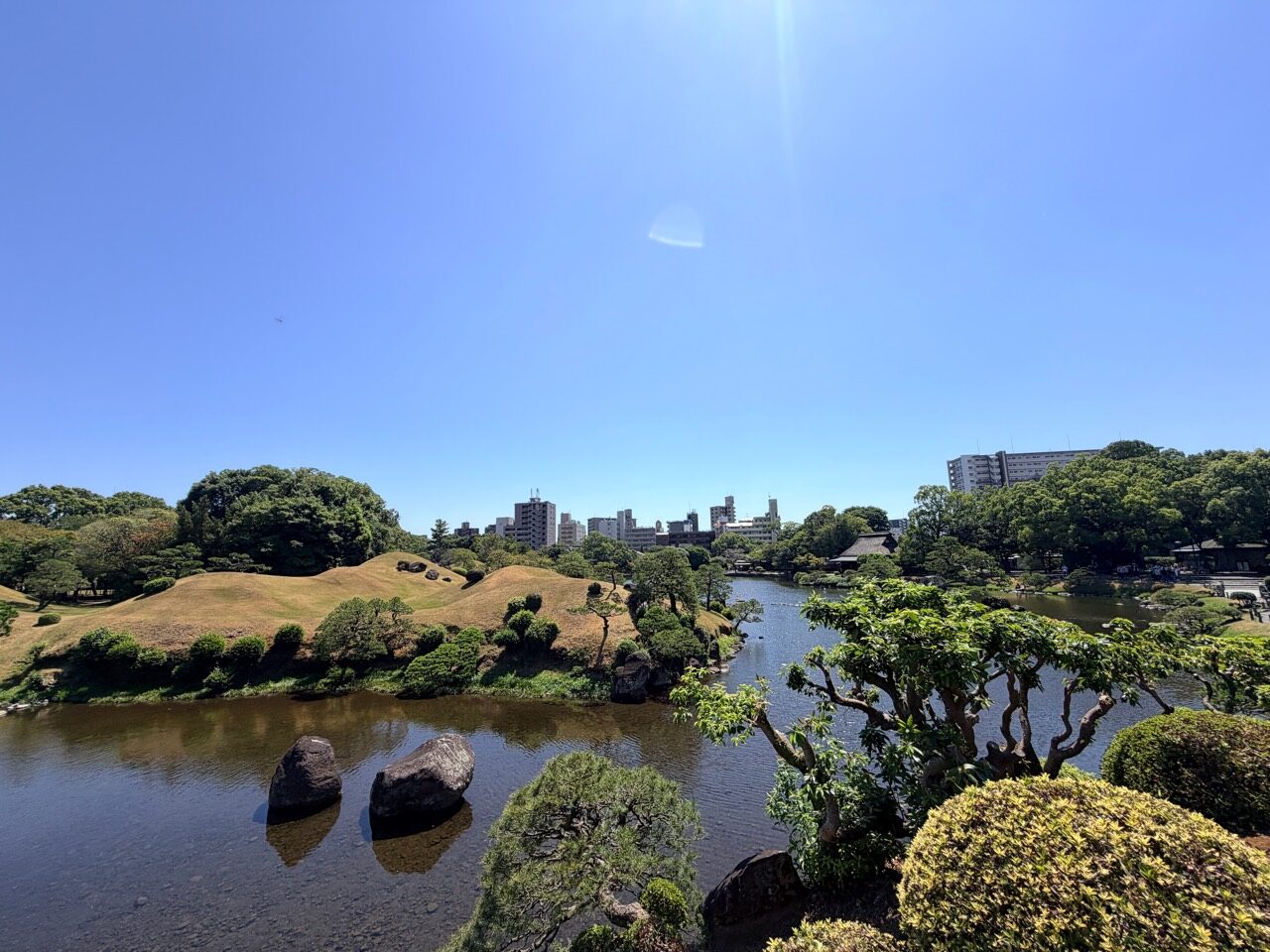 水前寺成趣園湧水池、小富士築山與熊本市區天際線