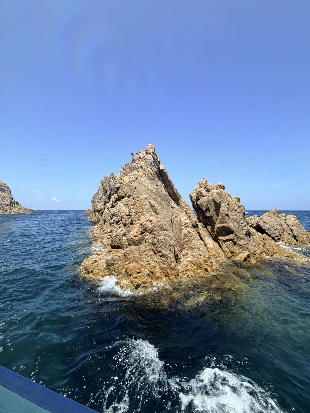 浦富海岸孤立礁岩與遊覽船航行尾浪