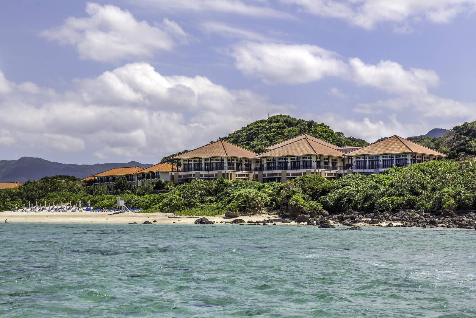 石垣島川平 Club Med 度假村｜度假村的紅瓦建築群立在草坡上，前方是海