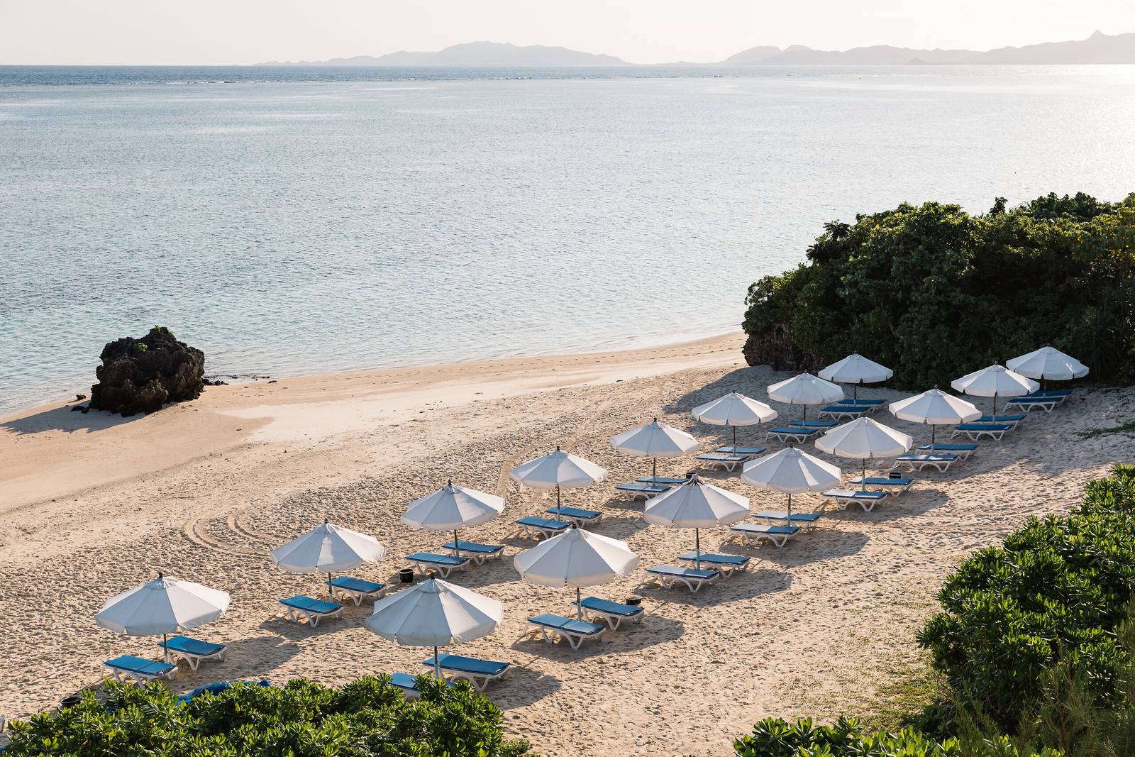 石垣島川平 Club Med 度假村｜沙灘上的一排藍白遮陽傘與躺椅