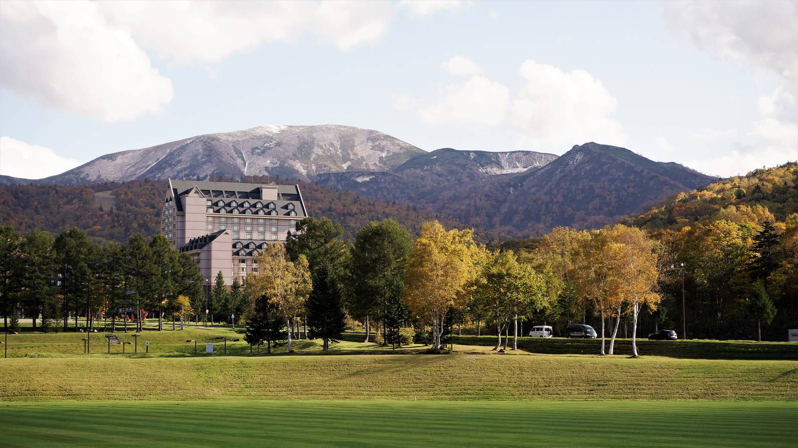 北海道喜樂樂 Grand 滑雪度假村｜夏季的度假村建築、草地與後方山脈