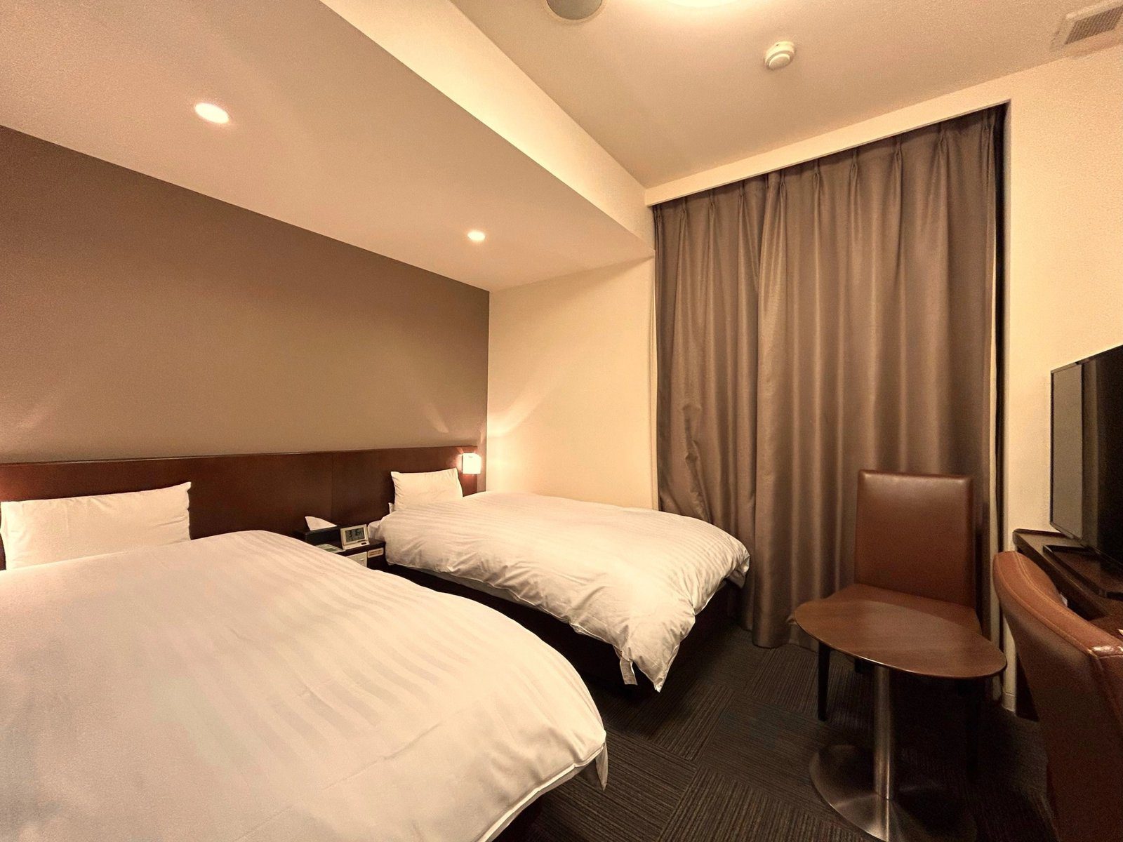 Dormy Inn 甲府 雙床房的兩張床與單人椅