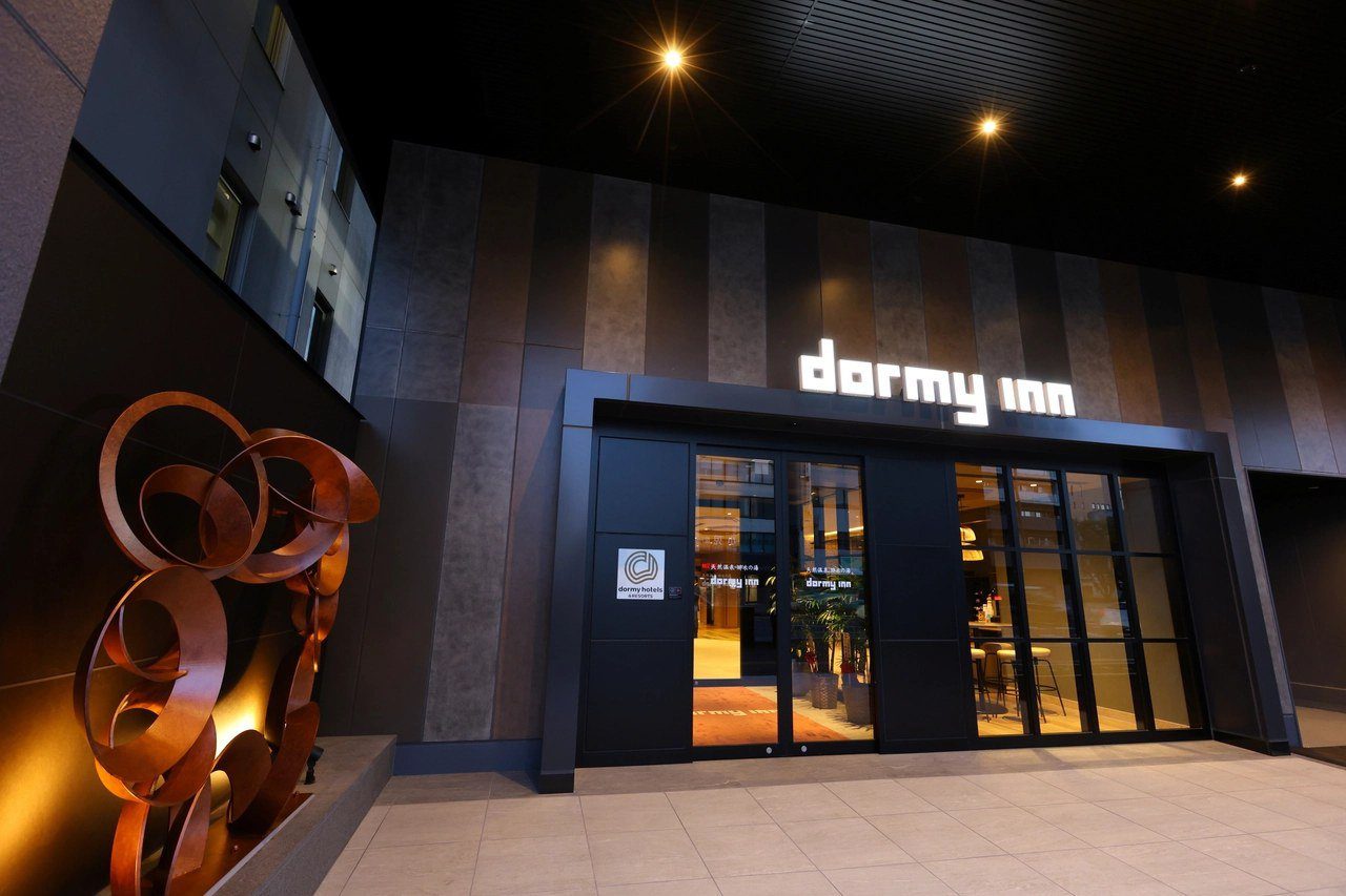 Dormy Inn 四日市 夜間的飯店入口與 dormy inn 招牌