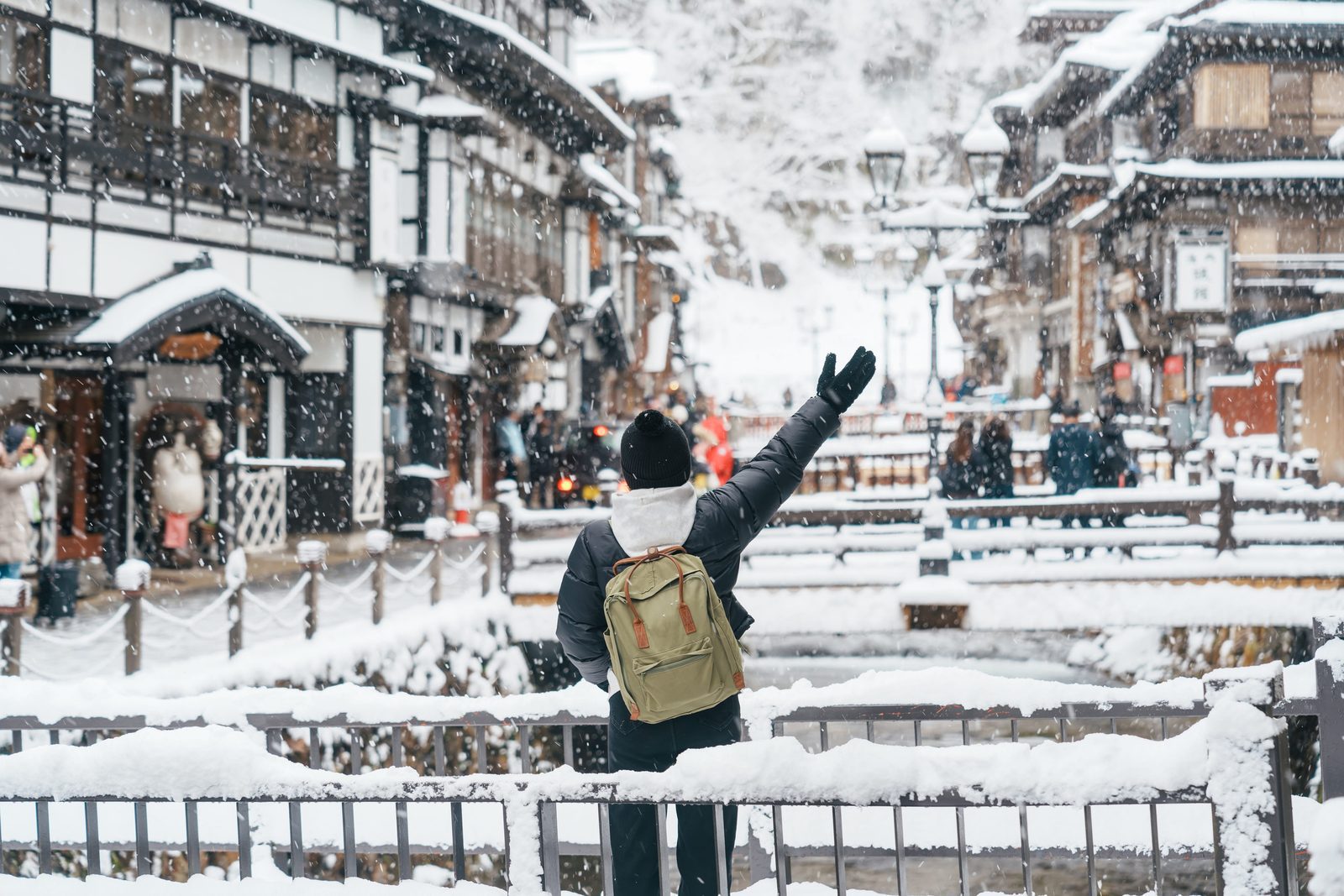 飄雪中的冬季銀山溫泉古老木造老街與漫步旅人背影
