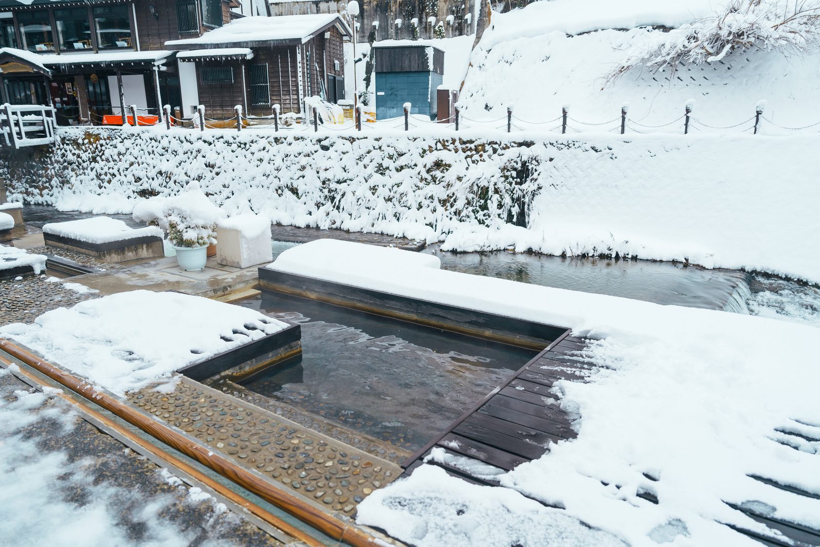冬季銀山溫泉入口處的和樂足湯覆雪池畔與溫泉水景