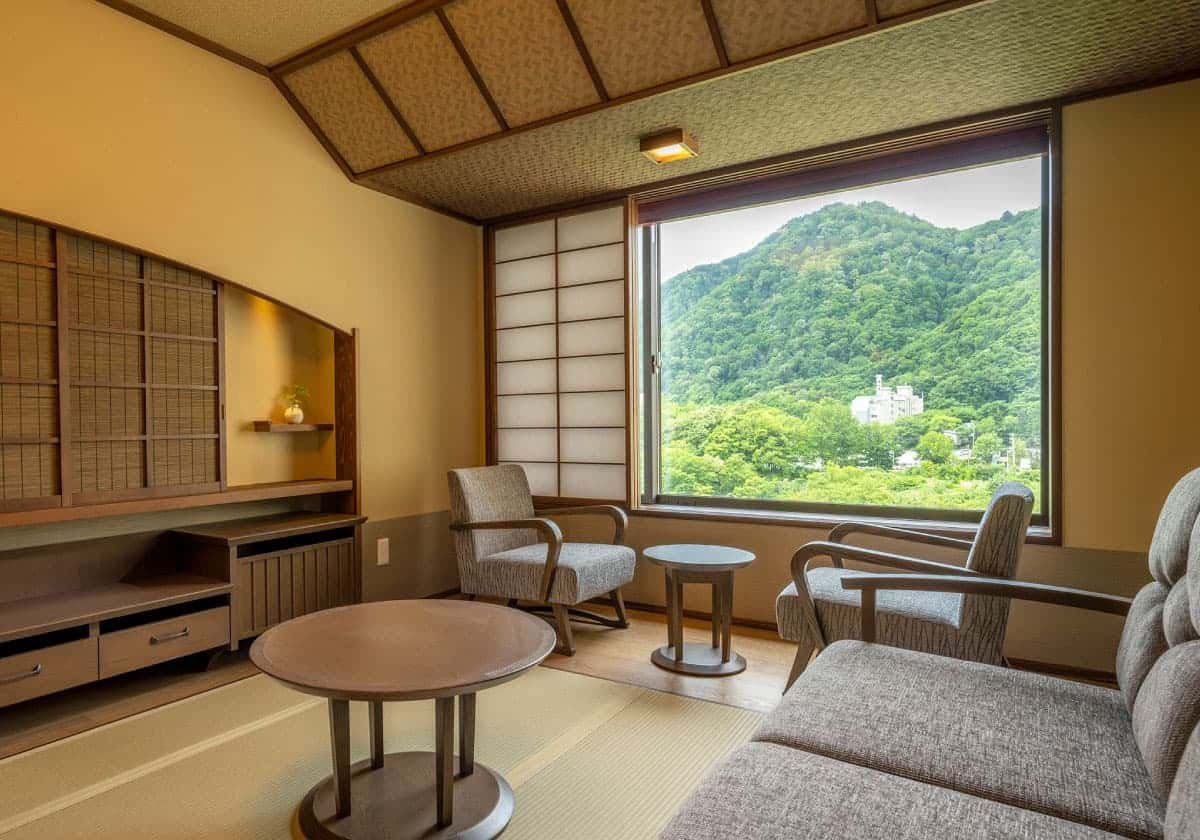 定山溪 由樂草庵 溪谷側客房的沙發區與窗外山景