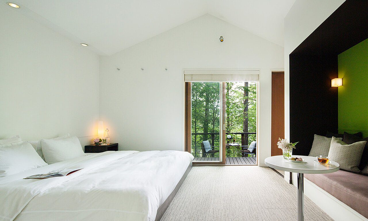 輕井澤 Hotel Bleston Court Terrace Villa 的白色雙人床與通往露台的落地門