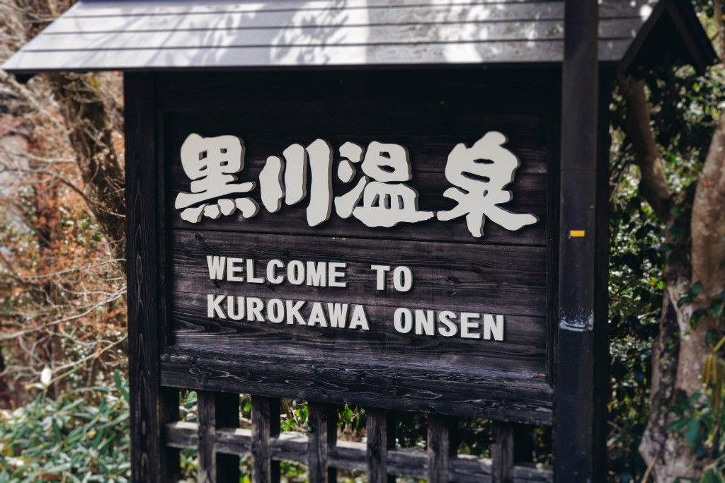 黑川溫泉木製歡迎牌，寫著黒川温泉與 Welcome to Kurokawa Onsen