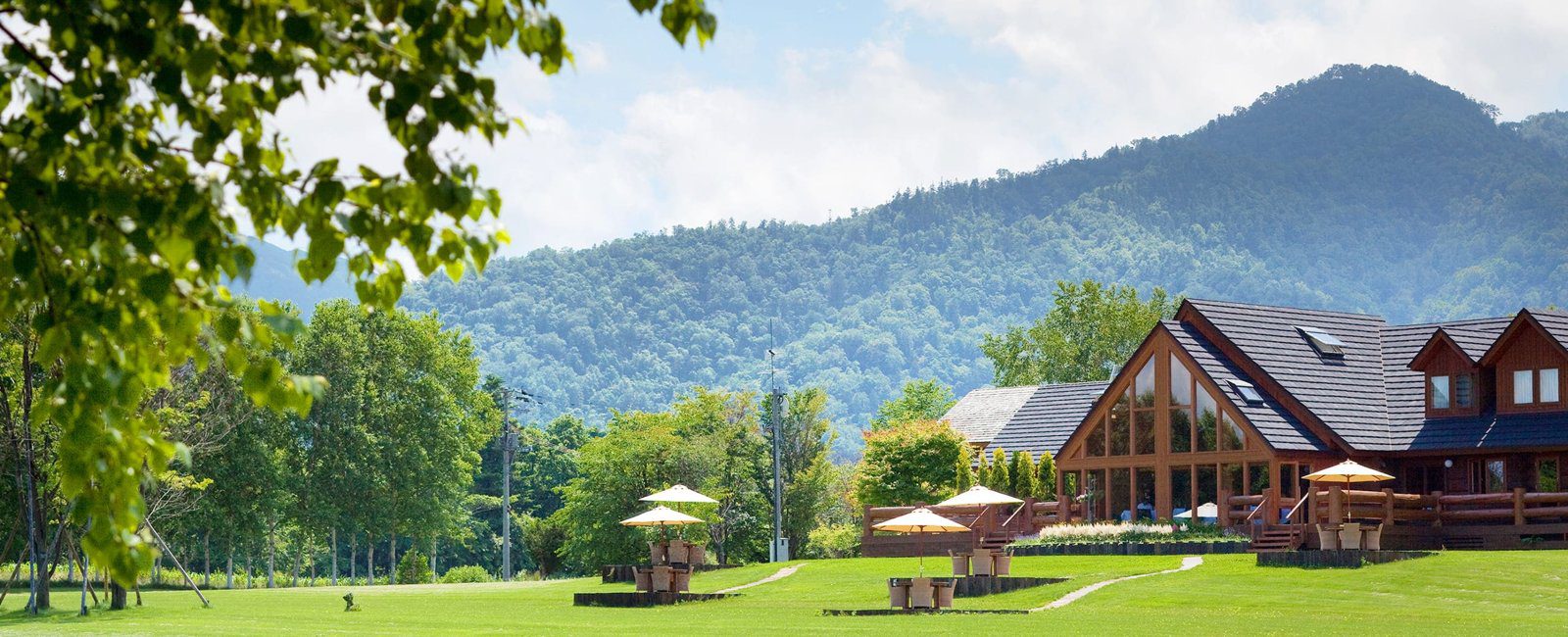 屈斜路湖 鶴雅 Auberge SoRa 樹林、草坪與遠方山稜間的原木屋