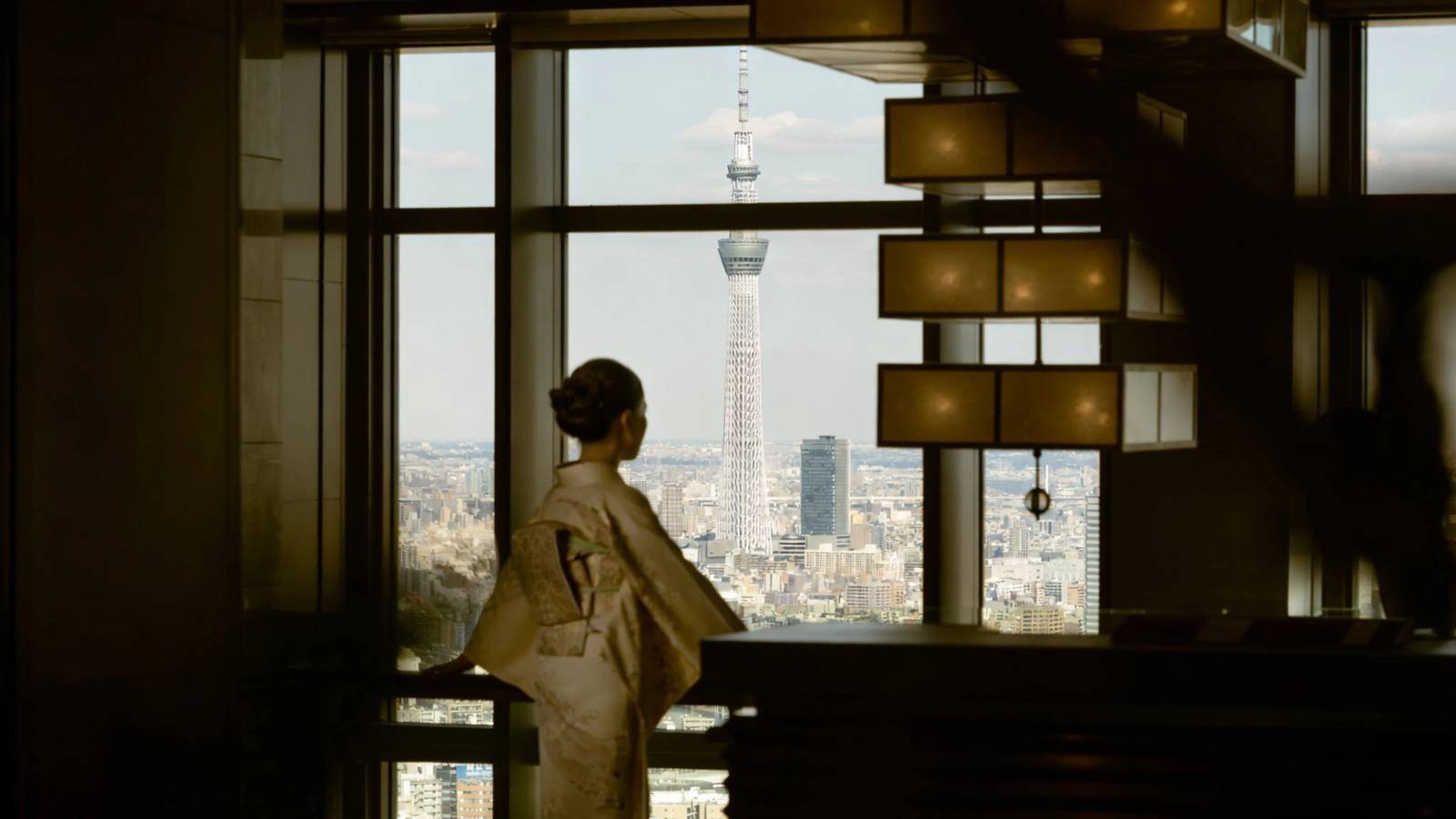 東京文華東方酒店 穿和服的女性站在 38 樓窗邊，遠方是東京晴空塔
