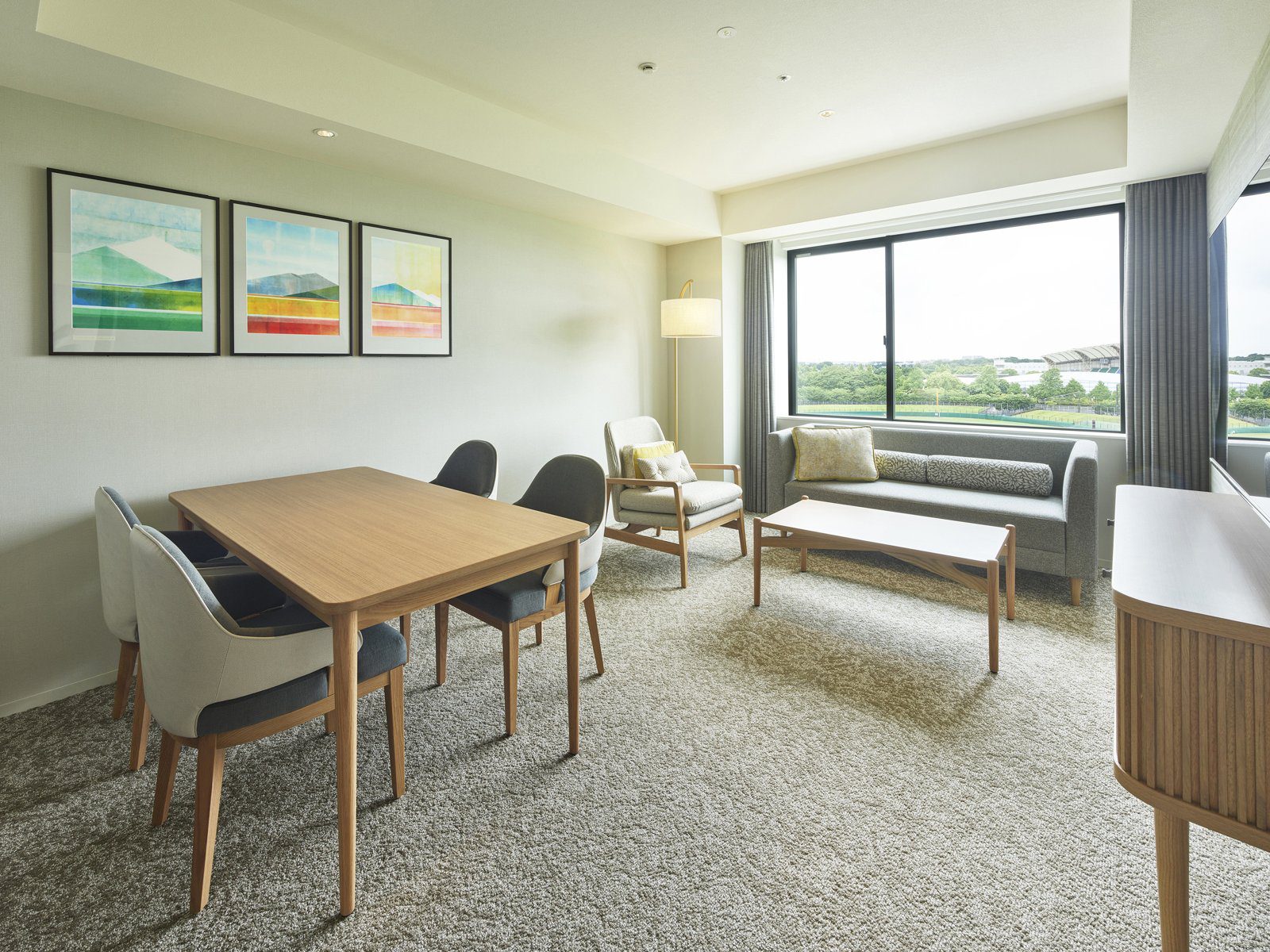 三井花園飯店 柏之葉 Park Side 套房客廳的餐桌、沙發與窗外綠地