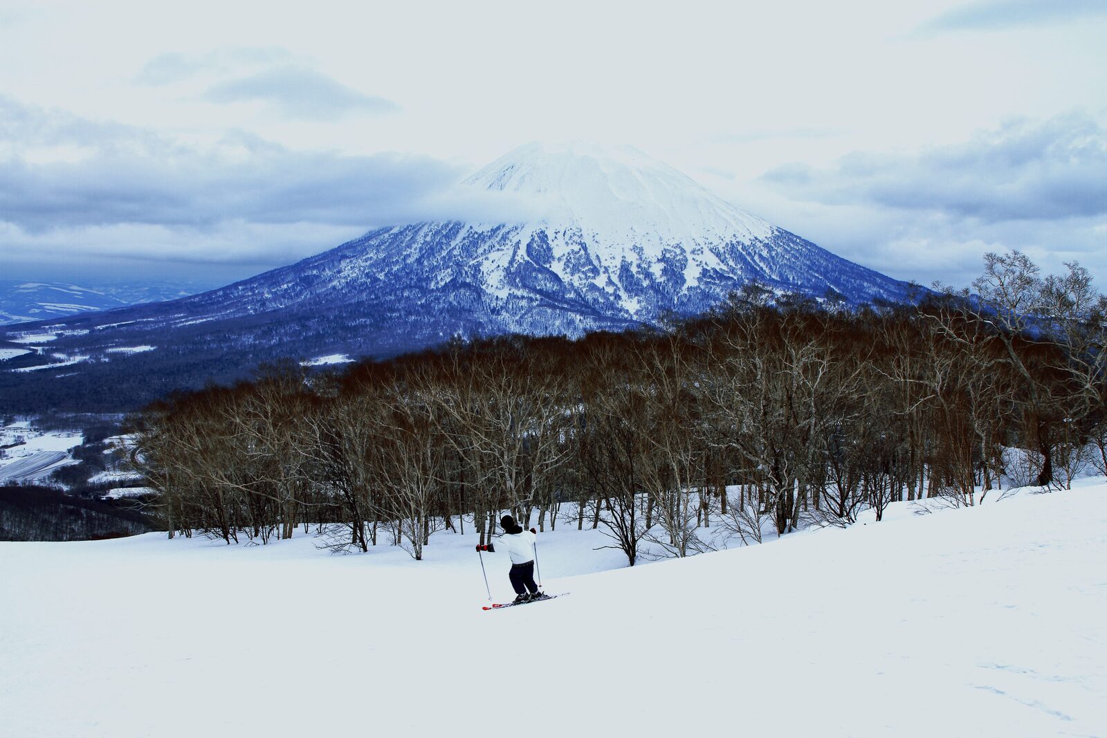 滑雪者行經雪道,遠方可見羊蹄山