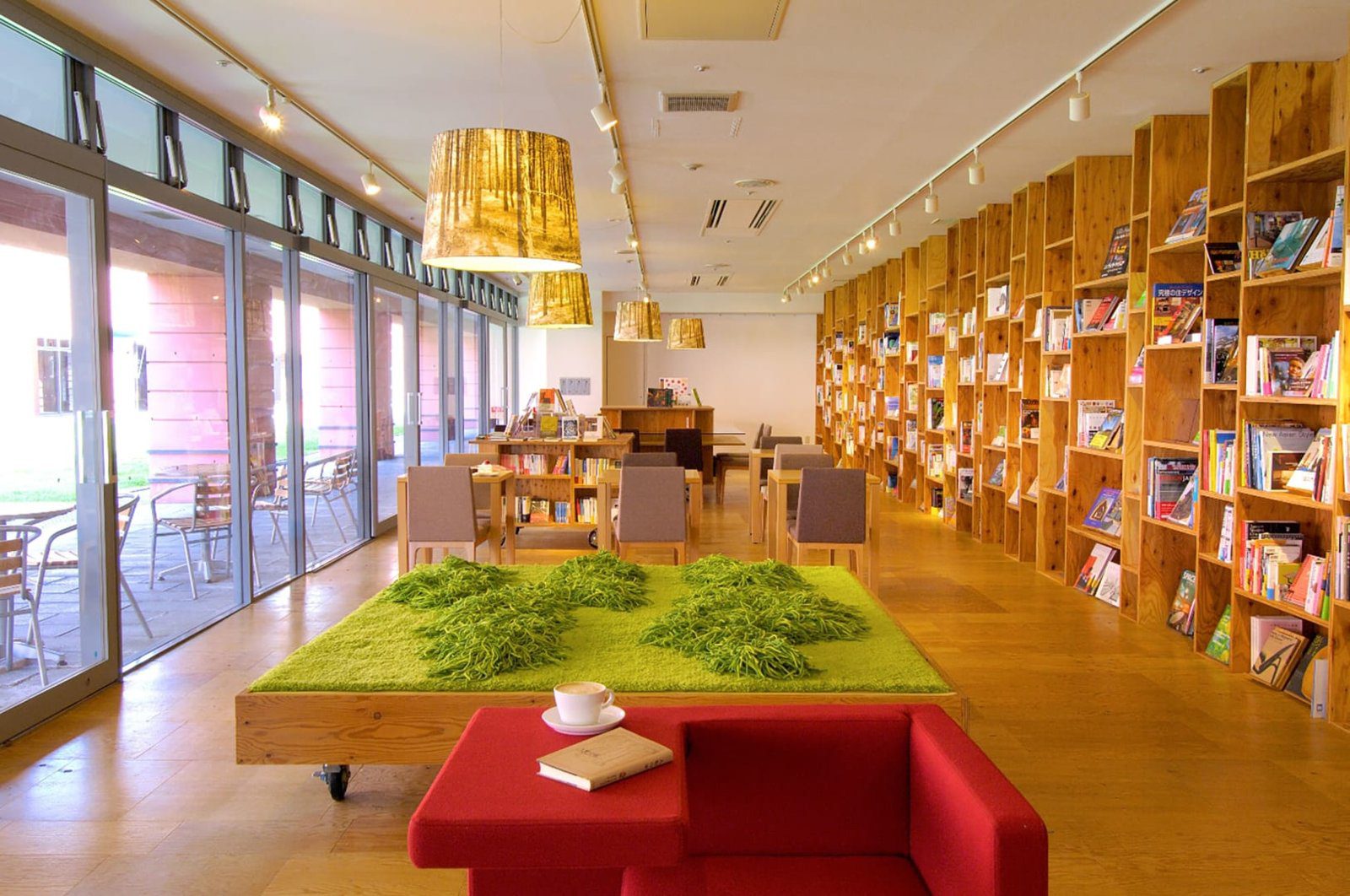 星野集團 RISONARE 八岳 Books & Cafe 的長排書牆、草皮造型桌與紅色沙發