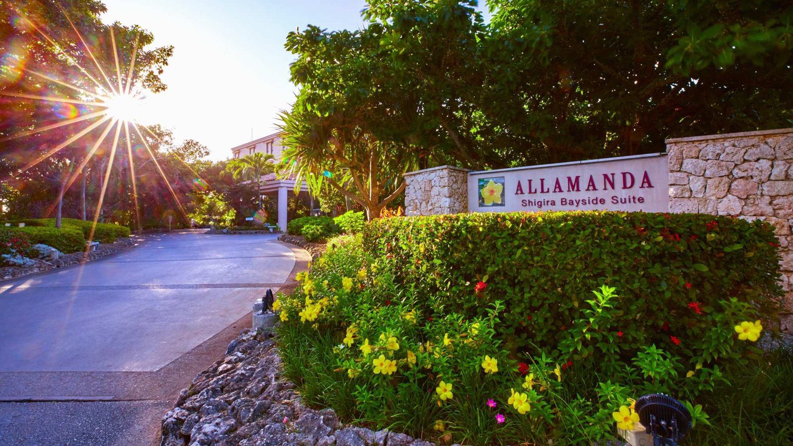 宮古島 Shigira Bayside Suite Allamanda 飯店入口的招牌與花叢